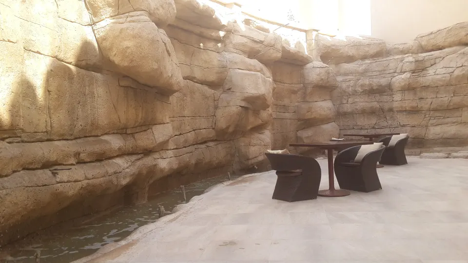 Rock-carved terrace seating beside a water channel at a destination development, Oman, 2014