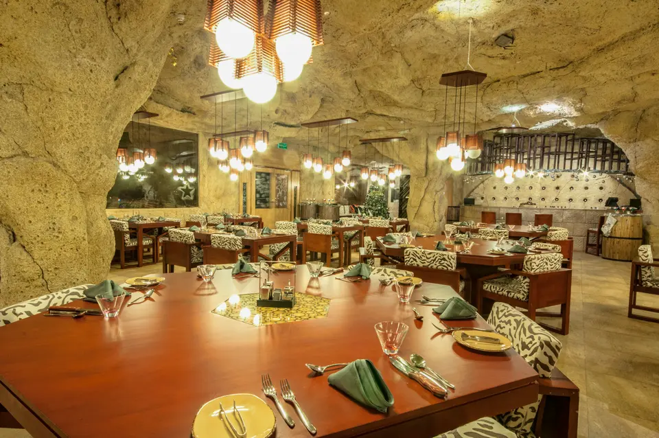A dining room set inside the carved rock interior, tables dressed and lit