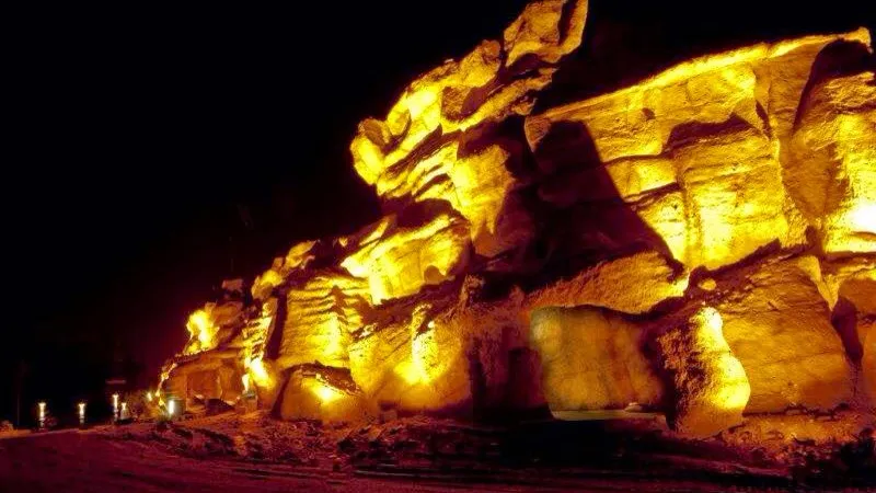 The illuminated rock facade of the destination complex at night, entrance lit from within